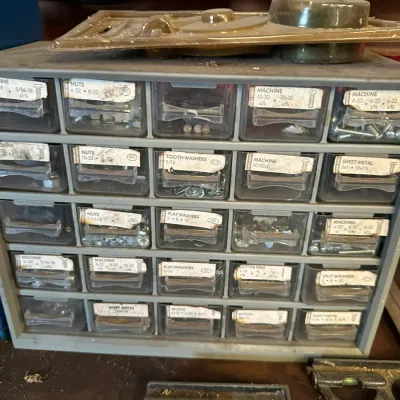 Sale Photo Thumbnail #507: Vintage metal parts organizer cabinet with plastic drawers filled with labeled hardware, including nuts, washers, and machine screws.