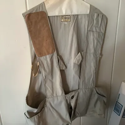Sale Photo Thumbnail #612: Vintage Gun Club Sportswear shooting vest in tan with a quilted shoulder recoil pad, shell pockets, and large game pouch.