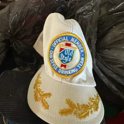 Sale Photo Thumbnail #603: Vintage white trucker hat featuring a embroidered 'Official Member Old Style Drinking Team' patch and gold oak leaf details on the brim.