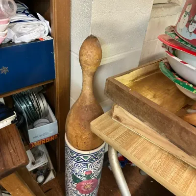 Sale Photo Thumbnail #289: A tall dried gourd displayed inside a cylindrical ceramic umbrella stand with hand-painted floral motifs.