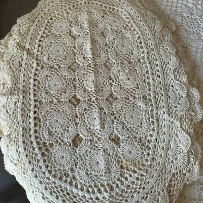 Sale Photo Thumbnail #607: Handmade oval crocheted lace doily in off-white, featuring an intricate floral medallion pattern and scalloped edges.