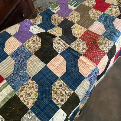 Sale Photo Thumbnail #582: Handmade vintage patchwork quilt featuring a bow tie or spool pattern in a variety of colorful patterned fabrics, displayed over a bed or bench.