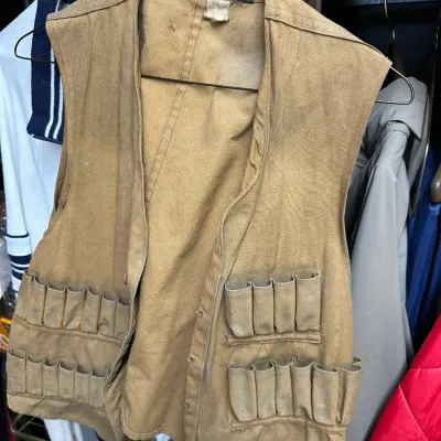 Sale Photo Thumbnail #83: Vintage tan canvas hunting vest by The Drybak Corp., featuring multiple shotgun shell loops and showing light wear consistent with age.