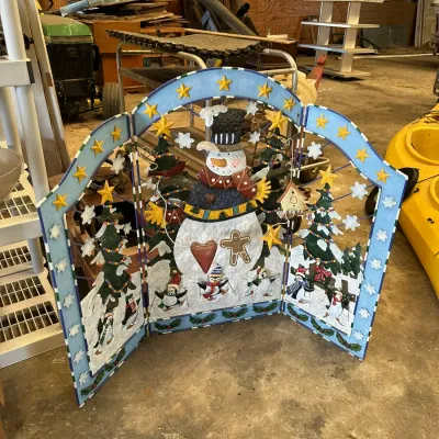 Sale Photo Thumbnail #568: Three-panel painted metal seasonal fireplace screen featuring a snowman, penguins, and pine trees.