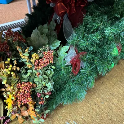 Sale Photo Thumbnail #26: Assortment of seasonal artificial greenery, featuring autumn berry picks and evergreen holiday garlands with decorative ribbons.
