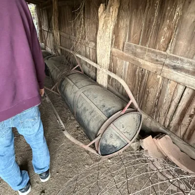 Sale Photo Thumbnail #331: Vintage pontoon log or cylindrical tank resting in a metal frame inside an outbuilding.