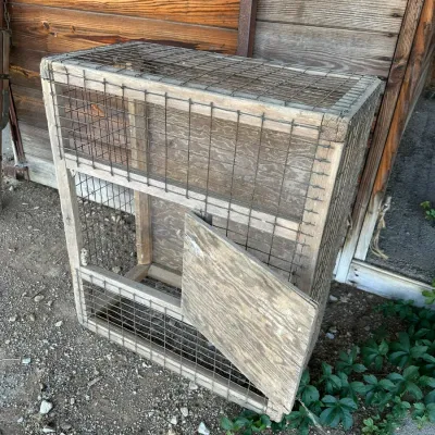 Sale Photo Thumbnail #177: Vintage rustic handmade wooden and wire mesh animal cage or coop featuring a hinged front door.