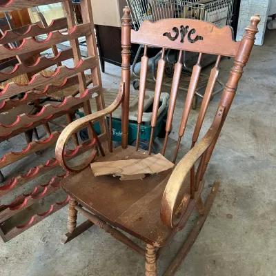 Sale Photo Thumbnail #734: Vintage wooden rocking chair featuring a cut-out heart motif on the top crest rail and turned spindle back supports, showing finish wear from age and use.
