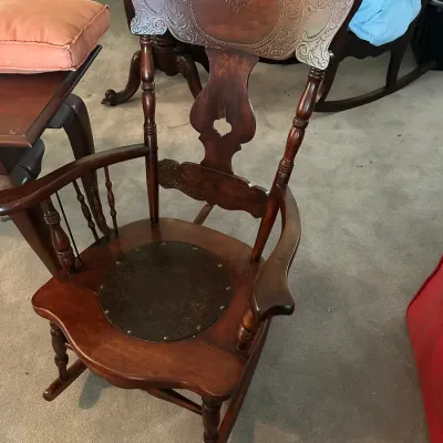 Sale Photo Thumbnail #580: Antique press-back wooden rocking chair featuring intricate carved scrollwork on the crest rail, turned spindles, and an embossed leather inset seat.