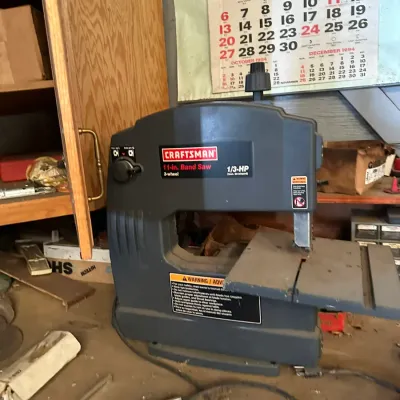 Sale Photo Thumbnail #499: Craftsman 11-inch 3-wheel, 1/3-HP benchtop band saw mounted on a dusty workshop table.