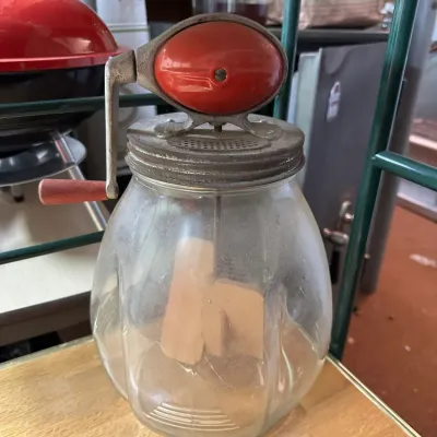 Sale Photo Thumbnail #86: Vintage glass butter churn with a hand crank mechanism, metal lid, and wooden paddles inside.