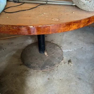Sale Photo Thumbnail #728: Mid-century round wooden table featuring a thick tabletop, a black metal support column, and a heavy domed pedestal base.