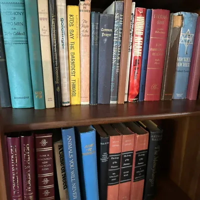 Sale Photo Thumbnail #649: Wooden bookshelf filled with vintage hardcover fiction and non-fiction books, including works by Taylor Caldwell and Ian Fleming.