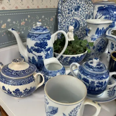 Sale Photo Thumbnail #704: Collection of blue and white ceramic transferware pieces, including a coffee pot, sugar bowls, creamer, mug, and decorative tray in traditional oriental patterns.
