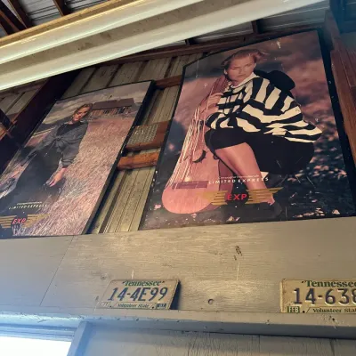 Sale Photo Thumbnail #495: Two vintage Compagnie Internationale Limited Express framed advertising posters mounted high on a wall alongside vintage Tennessee license plates.