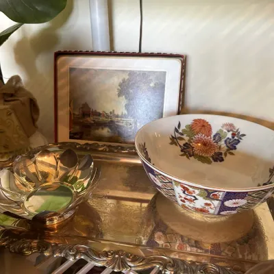 Sale Photo Thumbnail #681: Collection of decorative serving items featuring an ornate silver-plated tray, a silver-plated lotus petal bowl, an Imari-style floral porcelain bowl, and a framed art piece.