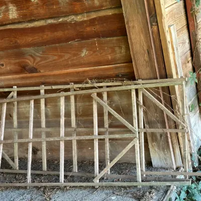 Sale Photo Thumbnail #269: Weathered wooden garden trellis sections resting against a rustic wooden structure.