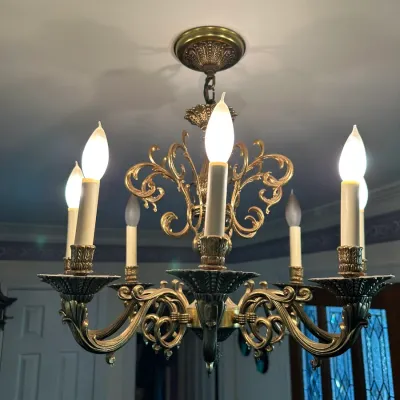 Sale Photo Thumbnail #709: Traditional brass six-light chandelier featuring ornate scrollwork arms, decorative bobeches, and faux candle sleeves.