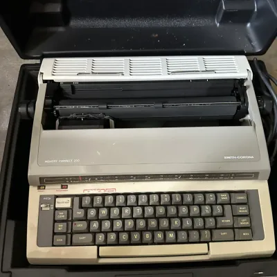 Sale Photo Thumbnail #461: Vintage Smith-Corona Memory Correct 200 portable electric typewriter housed in a hard black plastic carrying case, circa 1980s.