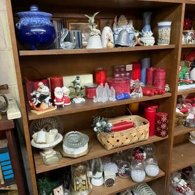 Sale Photo Thumbnail #46: Tall wooden bookcase displaying a large collection of home decor, including cobalt blue pottery, Christmas candles, ceramic Santa figurines, and decorative glassware.