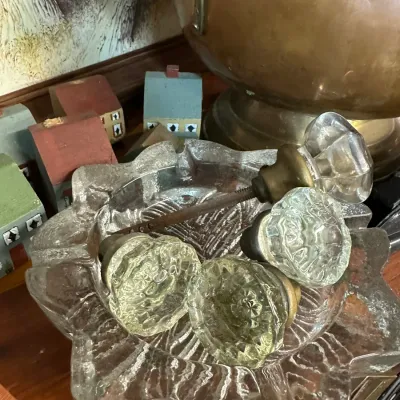 Sale Photo Thumbnail #56: Collection of vintage glass door knobs resting inside a clear textured glass star-shaped bowl.