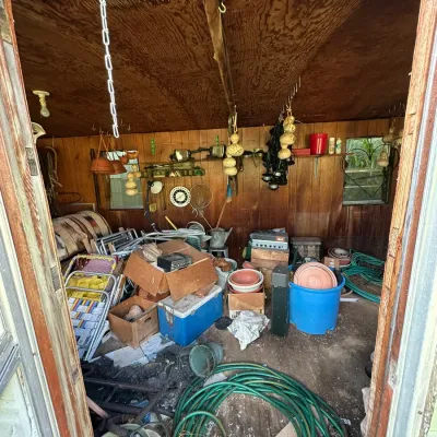Sale Photo Thumbnail #274: Storage shed filled with lawn and garden supplies, folding lawn chairs, garden hoses, plastic planters, and vintage hard coolers.