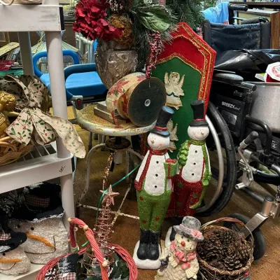 Sale Photo Thumbnail #70: Collection of holiday decorations, featuring standing glittered snowman figures, pinecone-filled baskets, a decorative floral centerpiece on a vintage stool, and additional Christmas accents.
