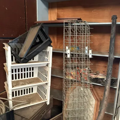 Sale Photo Thumbnail #537: Tall wire display or storage rack alongside stacked plastic utility crates and miscellaneous garage shelving units.