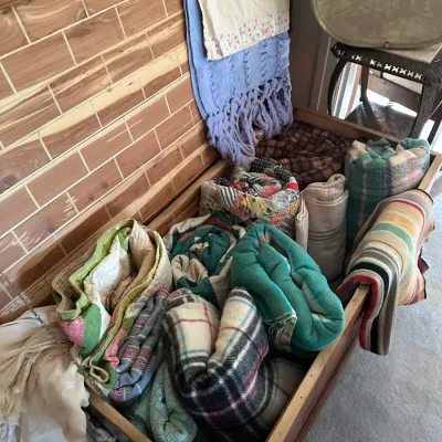 Sale Photo Thumbnail #199: Vintage cedar chest filled with a collection of textiles, including handmade quilts, wool blankets, and linens.