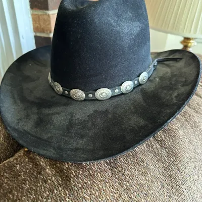 Sale Photo Thumbnail #628: Black felt cowboy hat featuring a leather hatband adorned with silver-tone conchos and studs.