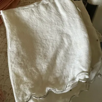 Sale Photo Thumbnail #598: Folded white linen napkins featuring scalloped edges with grey contrast embroidery.