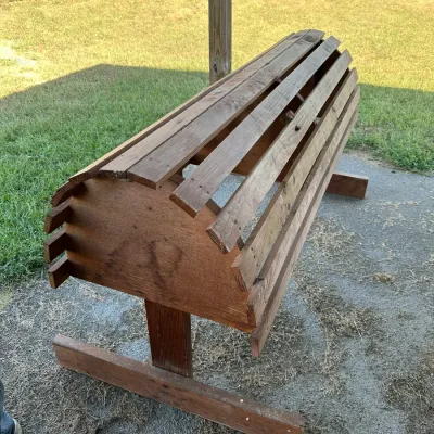 Sale Photo Thumbnail #176: Handcrafted wooden saddle rack stand featuring slatted construction and a sturdy T-base, positioned outdoors on a paved area.