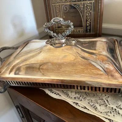Sale Photo Thumbnail #671: Vintage silver-plated rectangular chafing dish with ornate top handle, side handles, and scrolled feet showing surface patina.