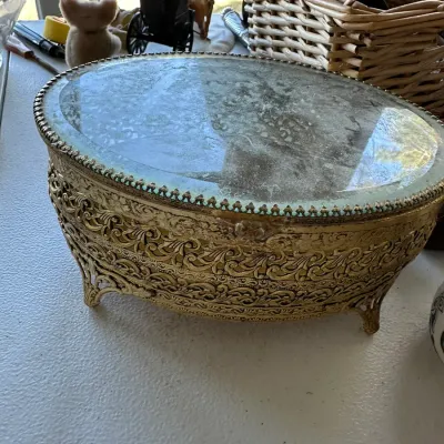 Sale Photo Thumbnail #386: Vintage Matson-style ornate gilt metal vanity box with an oval mirror lid and intricate filigree details.