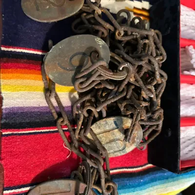 Sale Photo Thumbnail #371: Vintage rusted iron surveyor's Gunter's chain featuring numbered brass tags, showing heavy patina.