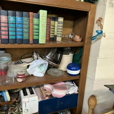 Sale Photo Thumbnail #291: Wooden bookcase filled with assorted vintage books, household knick-knacks, glassware, and small appliances including a toaster and coffee carafe.