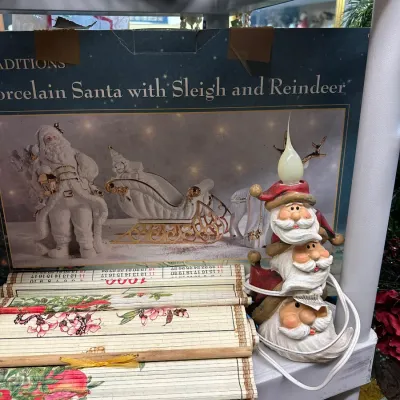 Sale Photo Thumbnail #69: Novelty electric stacked Santa head night light alongside a box for a porcelain Santa set and floral bamboo placemats.