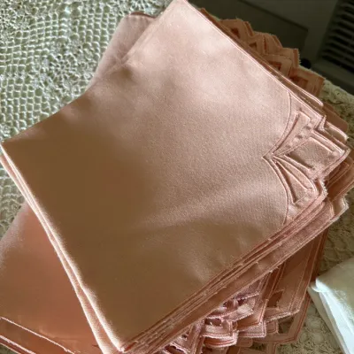 Sale Photo Thumbnail #597: Stack of vintage peach linen cloth napkins with embroidered fan-style corner details, resting on a crocheted tablecloth.