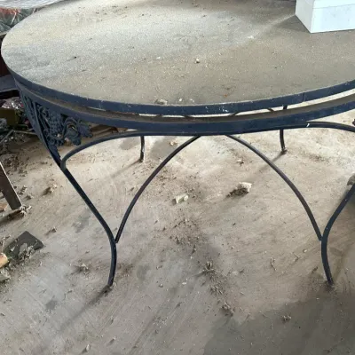 Sale Photo Thumbnail #739: Vintage black wrought iron patio table with grapevine motif along the apron and curved leg supports, showing heavy surface dust.