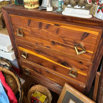 Sale Photo Thumbnail #298: Mid-century knotty pine three-drawer dresser featuring geometric brass pulls and decorative items displayed on top.