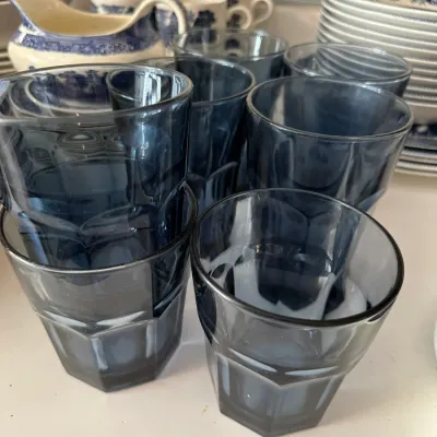 Sale Photo Thumbnail #697: Set of dark blue glass tumblers with faceted lower halves, displayed alongside blue and white transferware china.