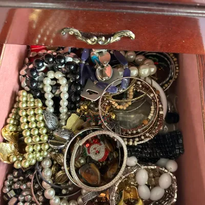 Sale Photo Thumbnail #144: Wooden jewelry chest drawer filled with assorted costume jewelry, including faux pearl strands, beaded bracelets, and bangles.