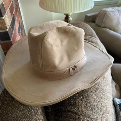 Sale Photo Thumbnail #637: Tan suede or soft leather cowboy hat featuring a matching hatband with a small metallic emblem.