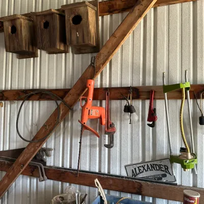 Sale Photo Thumbnail #731: Selection of workshop tools and items, including a vintage electric hedge trimmer, pipe wrenches, an oscillating lawn sprinkler, and handmade wooden birdhouses.