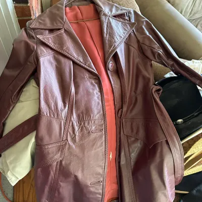 Sale Photo Thumbnail #611: Vintage 1970s women's burgundy leather trench coat with wide lapels and a matching waist belt.