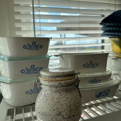 Sale Photo Thumbnail #692: Assortment of vintage CorningWare Blue Cornflower baking dishes with glass lids alongside a speckled ceramic clamp-lid jar.