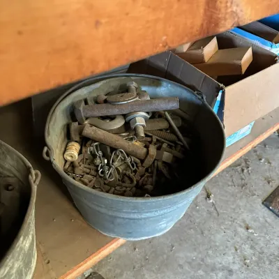 Sale Photo Thumbnail #505: Galvanized metal bucket filled with assorted vintage hardware, including large bolts, nuts, washers, and chains.