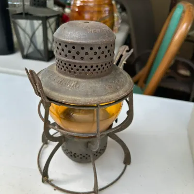 Sale Photo Thumbnail #166: Antique L.&N.R.R. metal railroad lantern with an amber glass globe, showing a rusted patina and vintage wear.