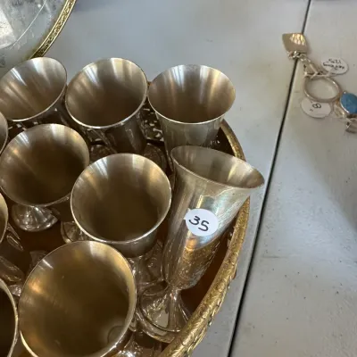 Sale Photo Thumbnail #400: Set of vintage silver-plated cordial stems displayed on a decorative brass-tone tray with a price sticker.