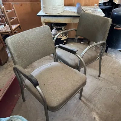 Sale Photo Thumbnail #721: Pair of mid-century industrial office armchairs featuring tubular metal frames with textured vinyl upholstery, showing heavy dust and wear.